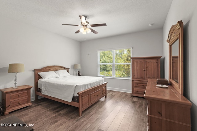 bedroom with a textured ceiling, ceiling fan, and dark wood-type flooring