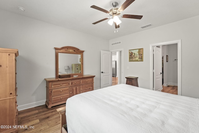 bedroom with ensuite bathroom, ceiling fan, and dark wood-type flooring