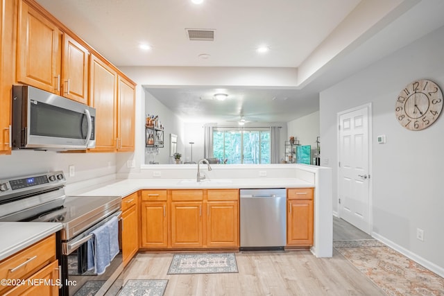 kitchen featuring kitchen peninsula, light wood-type flooring, stainless steel appliances, ceiling fan, and sink