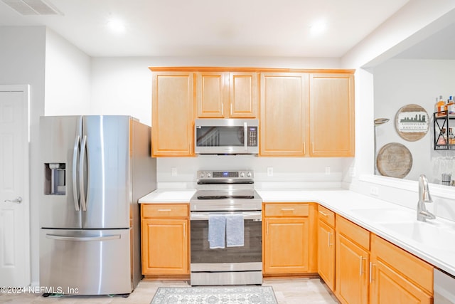 kitchen featuring light brown cabinets, stainless steel appliances, and sink