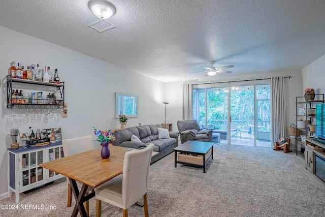 living room featuring carpet flooring, ceiling fan, and a textured ceiling