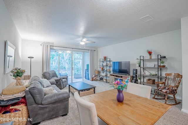 living room with a textured ceiling, carpet floors, and ceiling fan