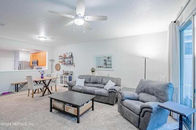 carpeted living room with ceiling fan and a textured ceiling