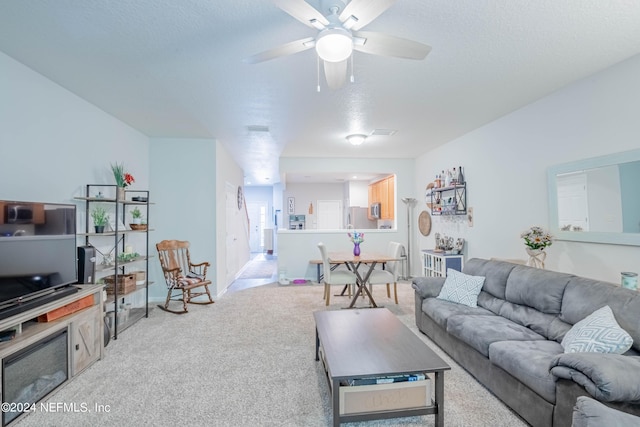 carpeted living room featuring ceiling fan and a textured ceiling