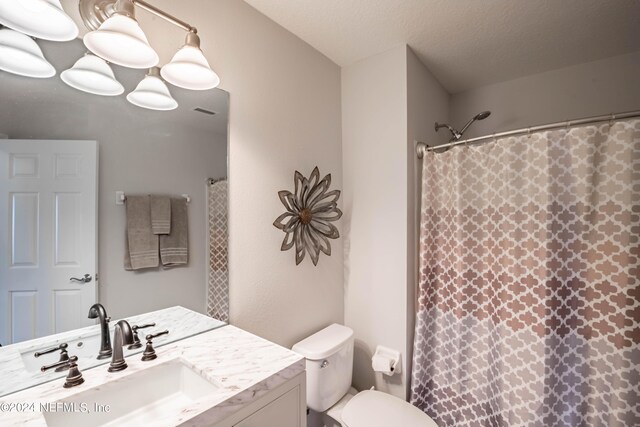 bathroom with a shower with shower curtain, vanity, toilet, and a textured ceiling