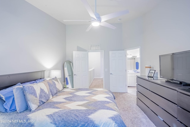 carpeted bedroom featuring ensuite bath, ceiling fan, and a high ceiling