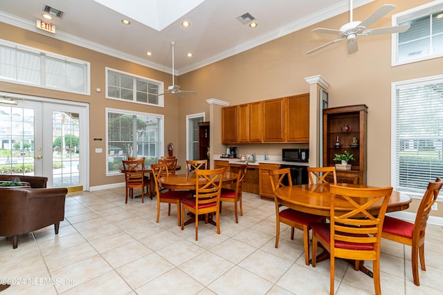 tiled dining room with french doors, a towering ceiling, ceiling fan, and ornamental molding