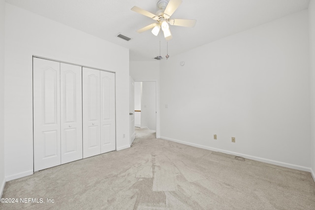 unfurnished bedroom with ceiling fan, light colored carpet, and a closet