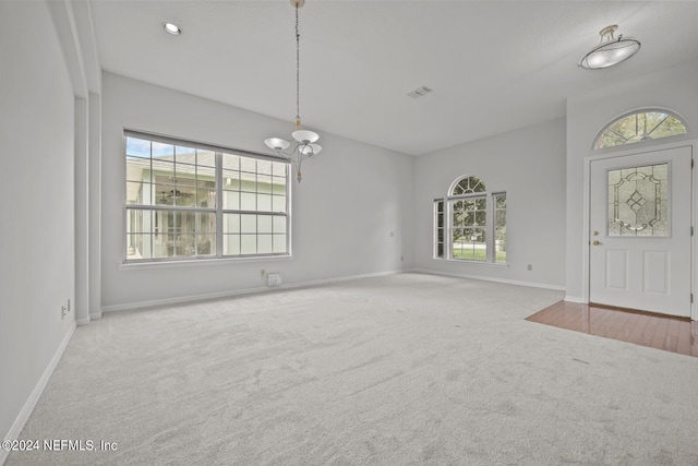 unfurnished living room featuring a chandelier and carpet flooring