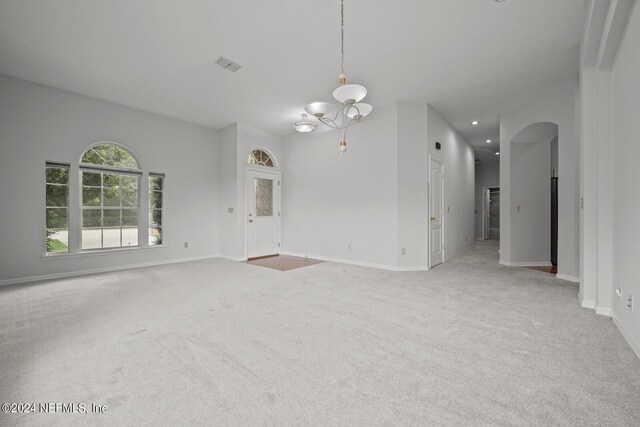 unfurnished living room with a chandelier and light colored carpet