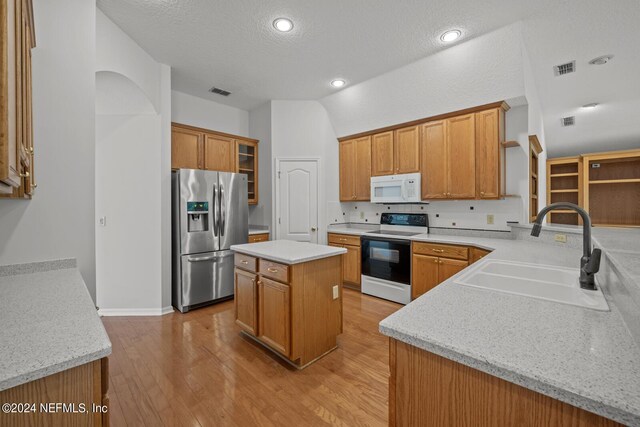 kitchen featuring light hardwood / wood-style flooring, white appliances, sink, light stone counters, and a kitchen island