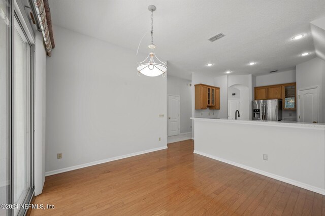 kitchen with sink, decorative light fixtures, stainless steel fridge with ice dispenser, and light wood-type flooring