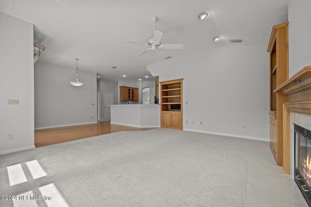 unfurnished living room with light carpet, a fireplace, ceiling fan, and vaulted ceiling