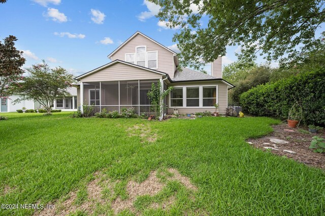 rear view of house with a sunroom and a lawn