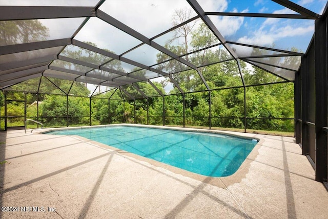 view of pool with glass enclosure and a patio