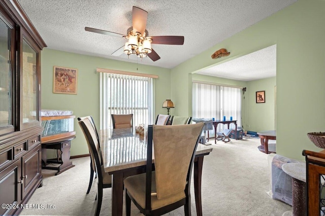 carpeted dining area with a textured ceiling and ceiling fan