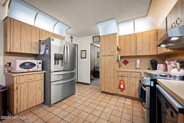 kitchen with a textured ceiling, stainless steel appliances, ventilation hood, and light tile flooring