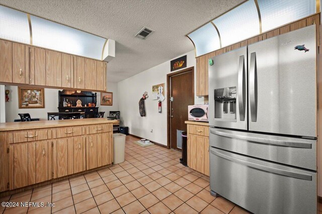 kitchen featuring a textured ceiling, light tile flooring, and stainless steel refrigerator with ice dispenser