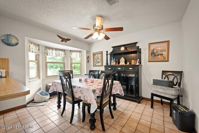 tiled dining space featuring ceiling fan and a textured ceiling