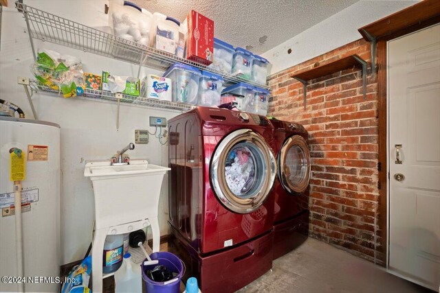 laundry area featuring water heater, a textured ceiling, and separate washer and dryer