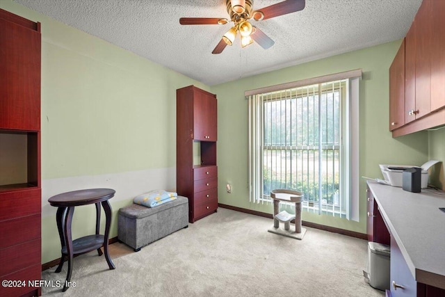 interior space featuring ceiling fan, a textured ceiling, and light carpet