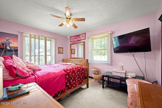 bedroom with ceiling fan, carpet floors, and a textured ceiling