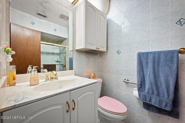 bathroom featuring tile walls, a textured ceiling, large vanity, and toilet