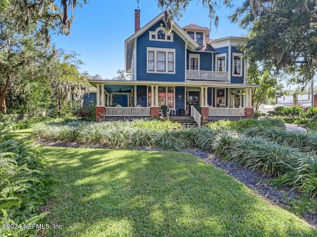 victorian home with a balcony, a front lawn, and covered porch