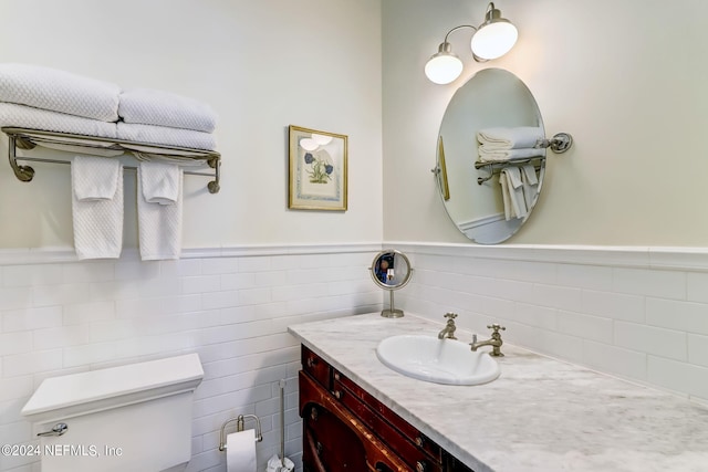 bathroom featuring vanity, toilet, and tile walls