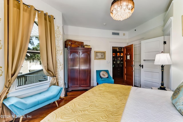 bedroom with a notable chandelier and dark wood-type flooring