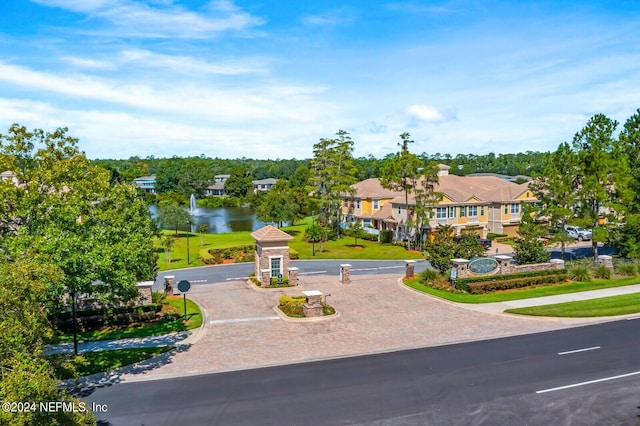 view of front of home with a water view, a residential view, curved driveway, and a front yard