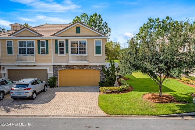 view of front of property featuring stone siding, an attached garage, decorative driveway, a front lawn, and stucco siding