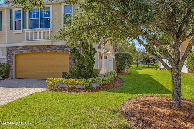 view of front of home featuring stone siding, an attached garage, decorative driveway, a front yard, and stucco siding