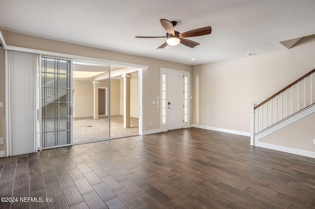 entryway featuring ceiling fan, dark wood-type flooring, stairway, and a textured ceiling