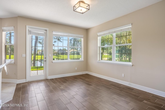 doorway featuring a textured ceiling, baseboards, and wood finished floors