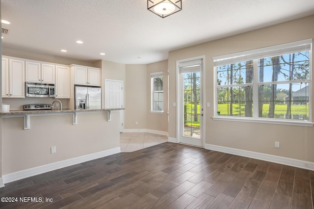 kitchen featuring light stone counters, a breakfast bar area, stainless steel appliances, and wood finished floors