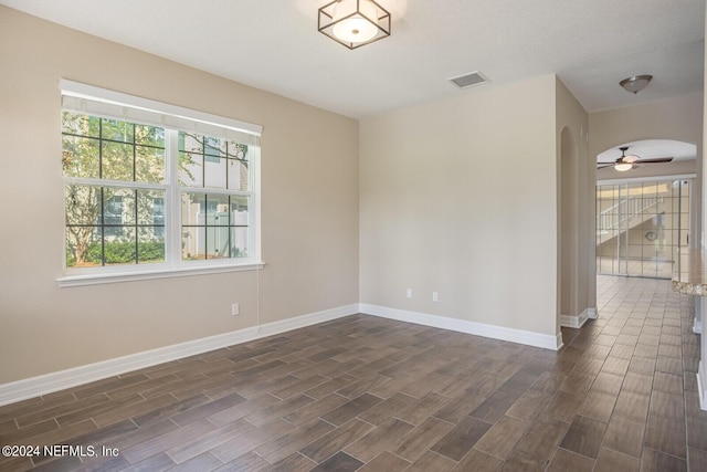 spare room with arched walkways, ceiling fan, wood finish floors, visible vents, and baseboards