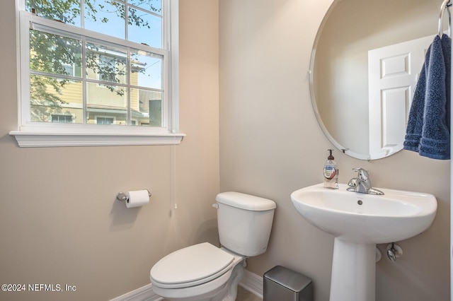 half bathroom featuring a sink, toilet, and baseboards