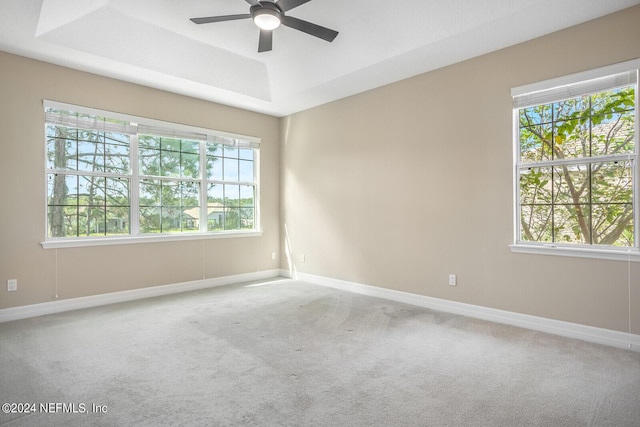 unfurnished room featuring carpet, baseboards, ceiling fan, and a raised ceiling