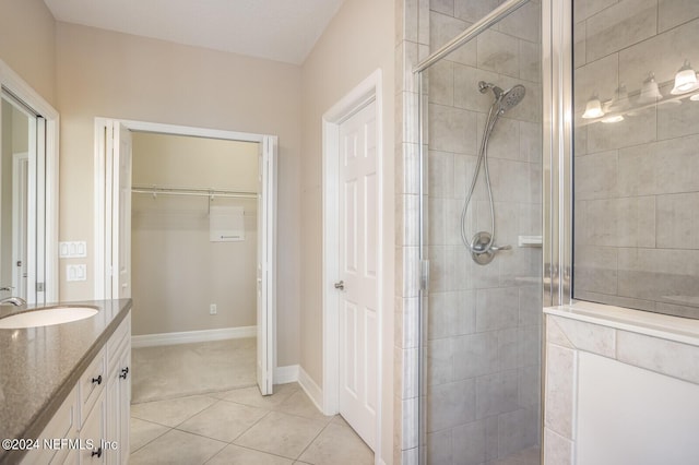 bathroom featuring baseboards, tile patterned floors, a walk in closet, vanity, and a shower stall