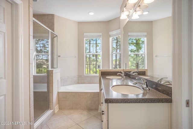 bathroom with a bath, a stall shower, tile patterned flooring, and a sink