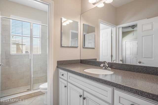 bathroom featuring a stall shower, tile patterned flooring, vanity, and toilet