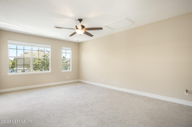 unfurnished room with baseboards, ceiling fan, attic access, and light colored carpet