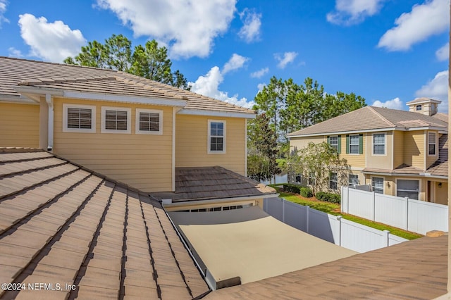 back of house featuring fence private yard and a tile roof