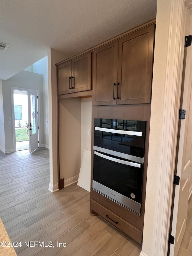 kitchen with a textured ceiling, light hardwood / wood-style floors, and double oven