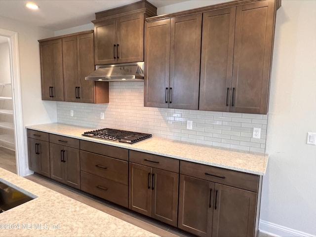 kitchen with dark brown cabinetry, sink, tasteful backsplash, light stone counters, and stainless steel gas stovetop