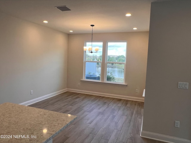 unfurnished dining area featuring a notable chandelier and dark hardwood / wood-style floors