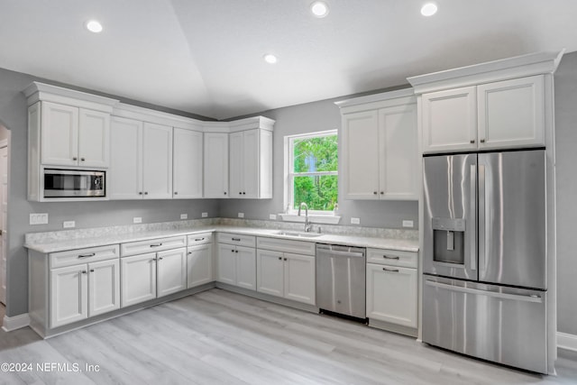 kitchen with white cabinets, stainless steel appliances, light hardwood / wood-style flooring, and sink