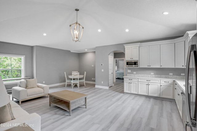 kitchen with white cabinetry, stainless steel microwave, pendant lighting, and lofted ceiling