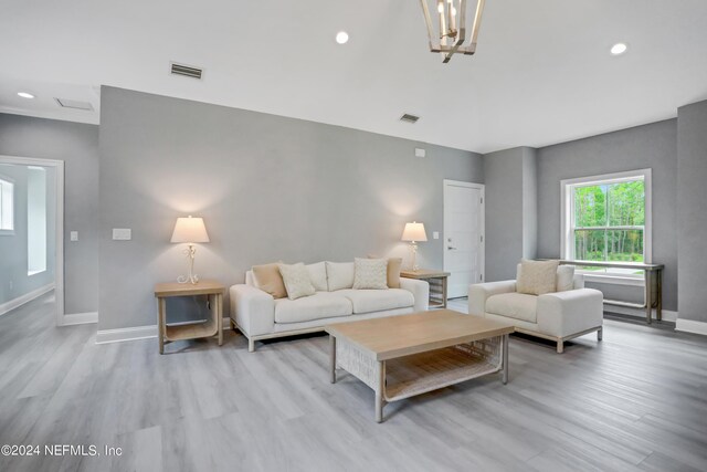 living room featuring light wood-type flooring and a notable chandelier